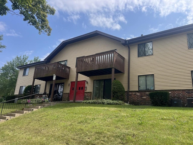 rear view of property with a balcony, a yard, and central AC