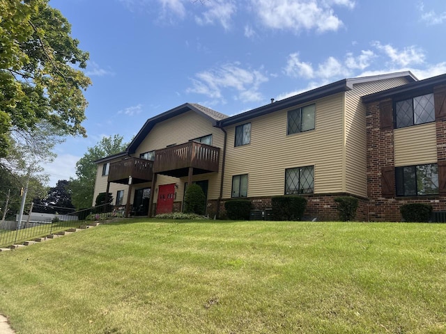 rear view of house featuring a balcony and a lawn