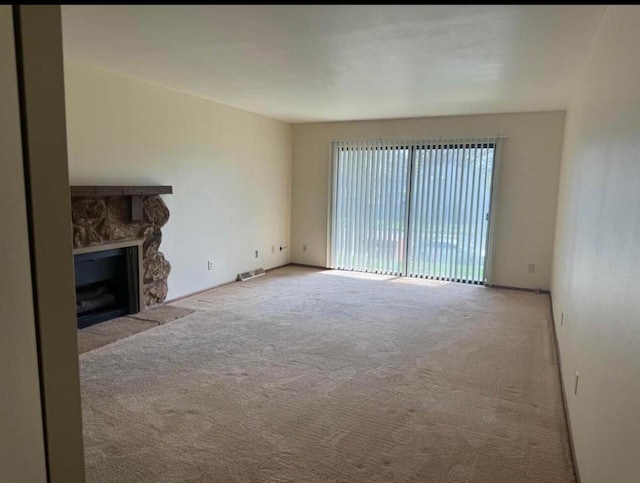 unfurnished living room with light colored carpet and a fireplace