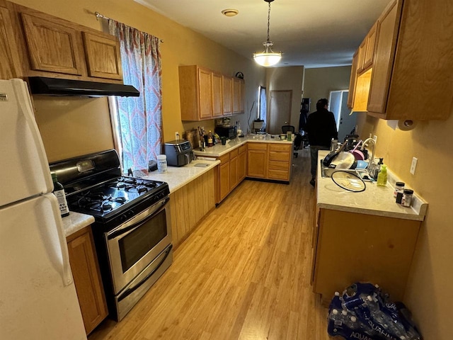 kitchen with white refrigerator, light hardwood / wood-style flooring, decorative light fixtures, gas stove, and kitchen peninsula