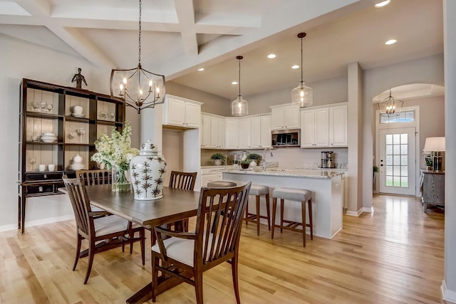 dining room with beamed ceiling, a notable chandelier, light hardwood / wood-style floors, and coffered ceiling