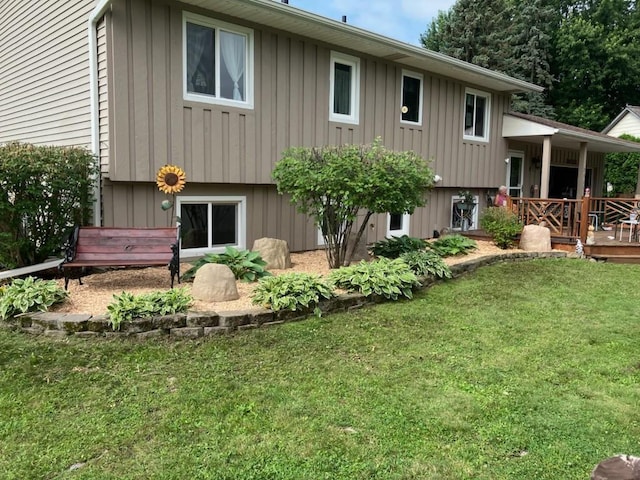 rear view of house featuring a wooden deck and a lawn