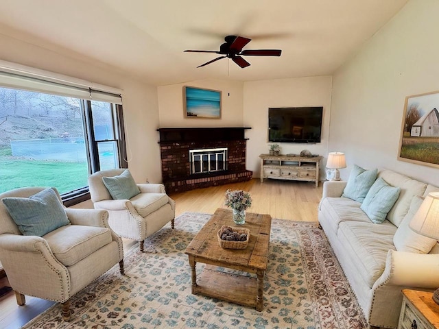 living room with ceiling fan, light hardwood / wood-style floors, and a brick fireplace