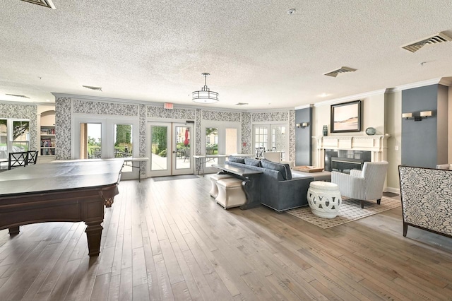 recreation room with french doors, a textured ceiling, ornamental molding, and wood-type flooring