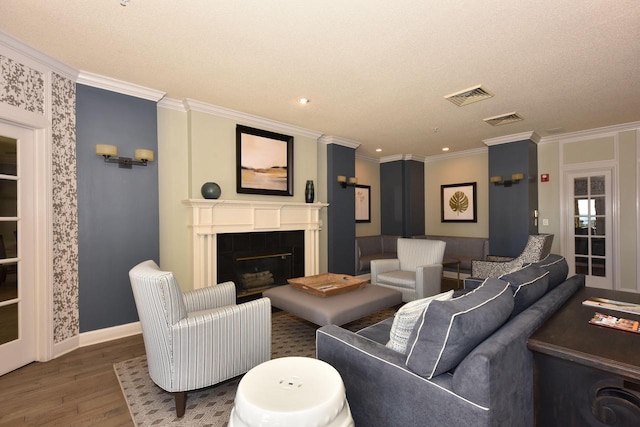 living room featuring wood-type flooring, a textured ceiling, and ornamental molding