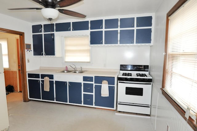 kitchen with blue cabinets, sink, white gas stove, and ceiling fan