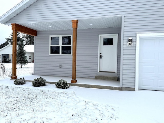 snow covered property entrance with a garage