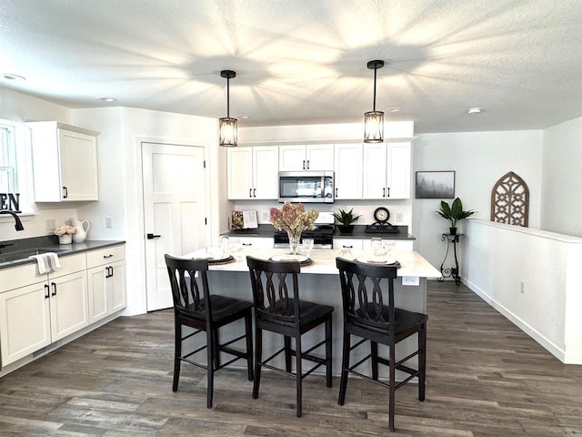 kitchen featuring appliances with stainless steel finishes, a kitchen island, white cabinetry, and pendant lighting