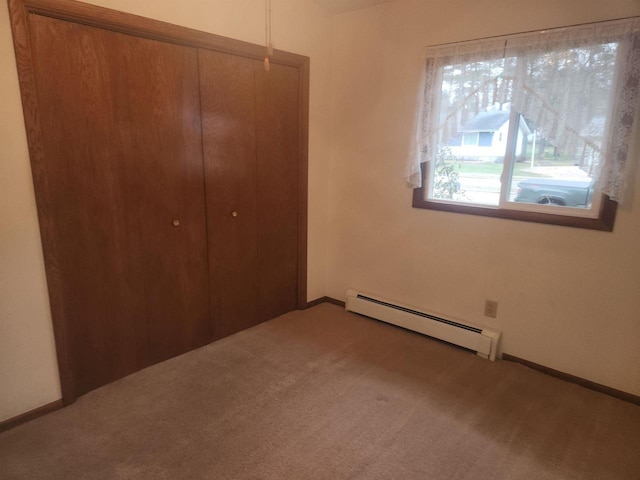 unfurnished bedroom with carpet floors, a baseboard radiator, and a closet