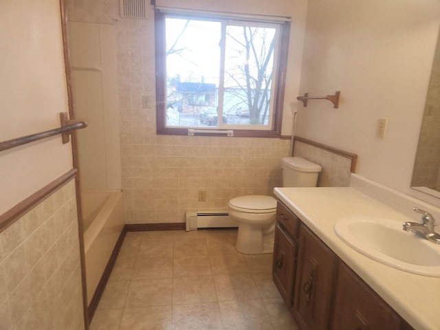 bathroom featuring baseboard heating, tile patterned flooring, toilet, vanity, and tile walls