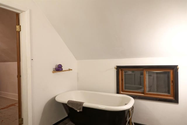 bathroom featuring a tub to relax in and lofted ceiling