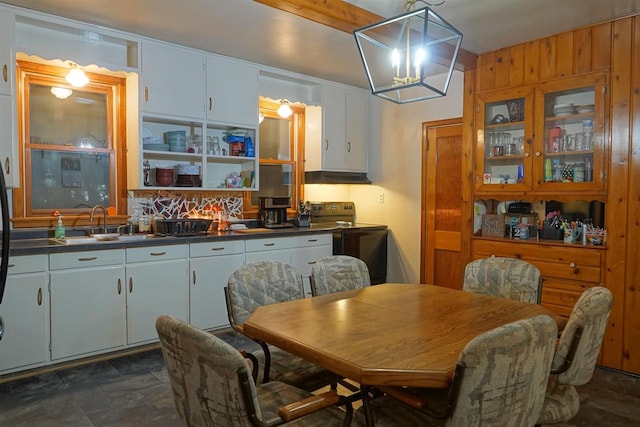 dining area with wood walls, sink, and a notable chandelier