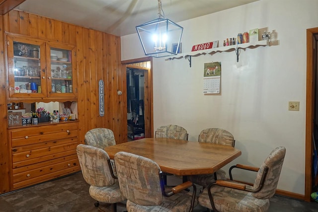 dining area with wooden walls and a chandelier