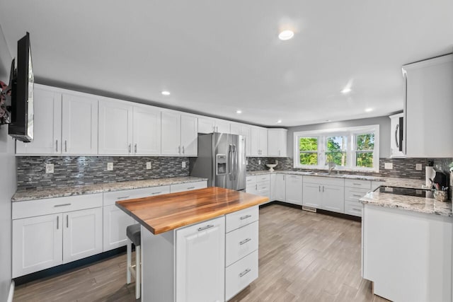 kitchen featuring a kitchen island, white cabinets, light wood-type flooring, and appliances with stainless steel finishes