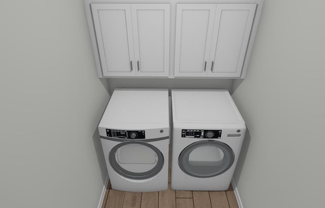 laundry area with cabinets, washing machine and dryer, and wood-type flooring