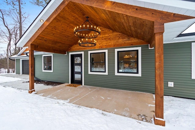 snow covered property entrance featuring a garage