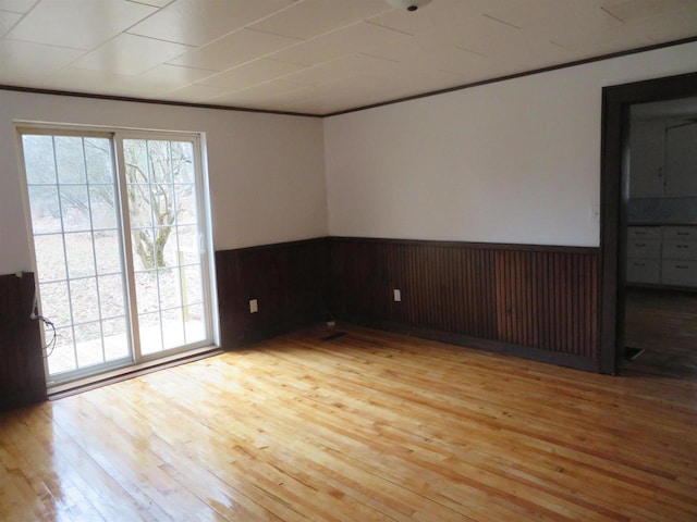 spare room with wood walls, light hardwood / wood-style flooring, and crown molding