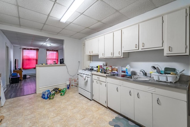 kitchen with a drop ceiling, white cabinetry, white gas range, and sink