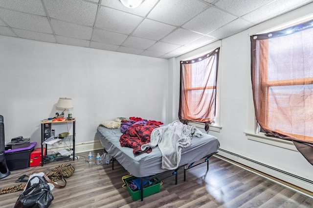 bedroom with hardwood / wood-style flooring, a paneled ceiling, and a baseboard radiator