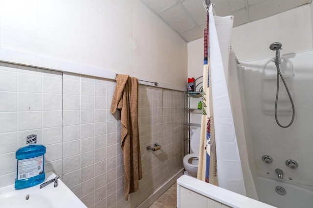 bathroom with tile patterned floors, shower / bath combination with curtain, toilet, and tile walls