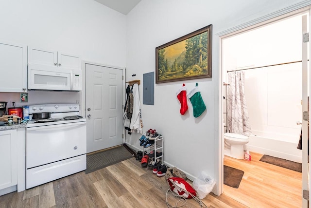 kitchen with white cabinets, electric panel, white appliances, and hardwood / wood-style flooring