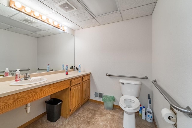 bathroom with a paneled ceiling, vanity, and toilet