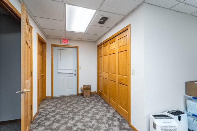 hall featuring carpet and a drop ceiling