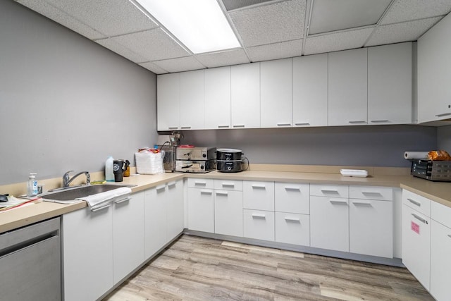 kitchen featuring white cabinets, stainless steel dishwasher, light wood-type flooring, and sink