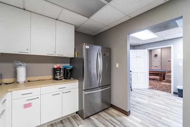 kitchen featuring stainless steel refrigerator, pool table, a paneled ceiling, white cabinets, and light wood-type flooring