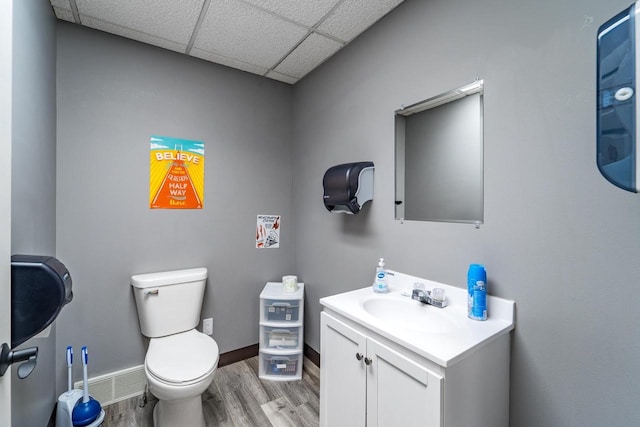 bathroom with hardwood / wood-style floors, vanity, a drop ceiling, and toilet