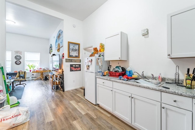 kitchen featuring white cabinets, white refrigerator, light wood-type flooring, and sink