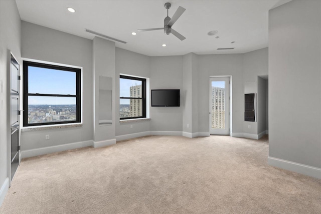 unfurnished living room featuring ceiling fan and light colored carpet
