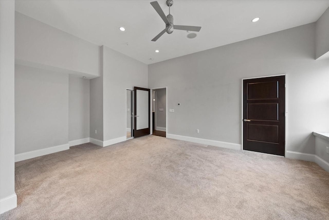 unfurnished bedroom featuring a high ceiling, light colored carpet, and ceiling fan
