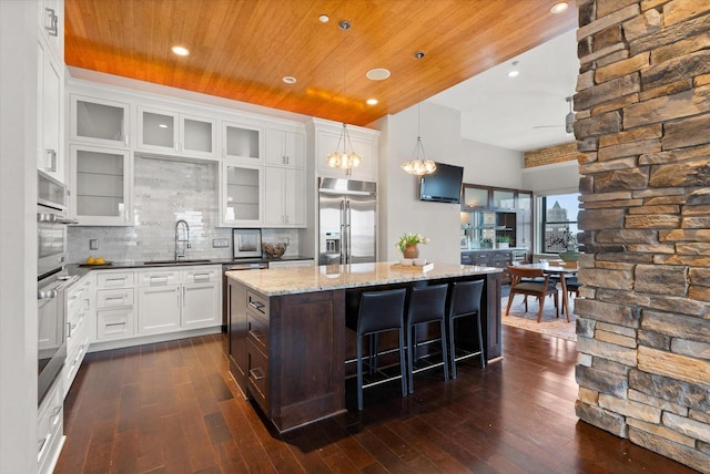 kitchen featuring dark hardwood / wood-style floors, a center island, stainless steel built in refrigerator, and white cabinetry