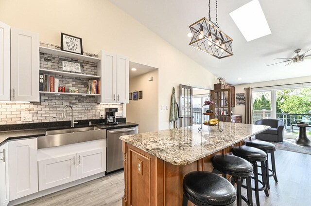 7134 N Tichigan Rd, Waterford, WI 53185 - kitchen featuring dishwasher, a sink, a skylight, light wood-style flooring, and backsplash