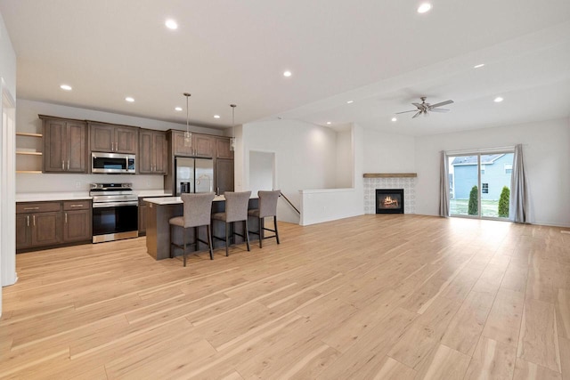 kitchen featuring pendant lighting, a kitchen island with sink, a breakfast bar area, light wood-type flooring, and stainless steel appliances