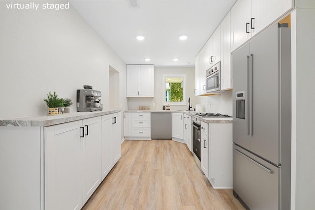 kitchen with white cabinets, light hardwood / wood-style floors, high quality appliances, and sink