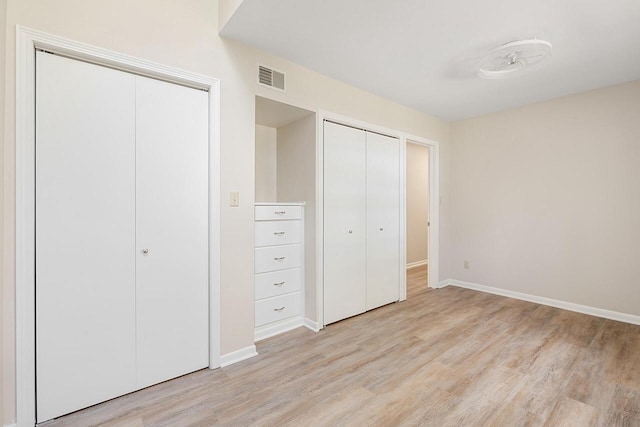 unfurnished bedroom with multiple closets and light wood-type flooring