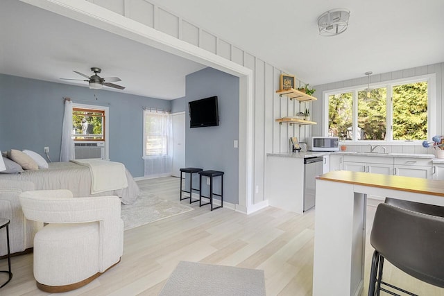 bedroom with ceiling fan, light hardwood / wood-style flooring, cooling unit, and sink