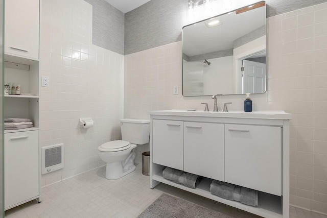 bathroom with tile patterned flooring, vanity, toilet, and tile walls