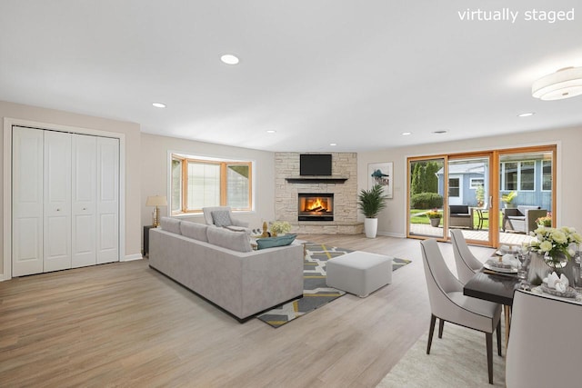 living room featuring light hardwood / wood-style flooring, a wealth of natural light, and a stone fireplace