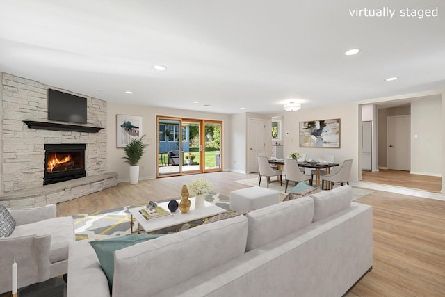 living room featuring light wood-type flooring and a stone fireplace