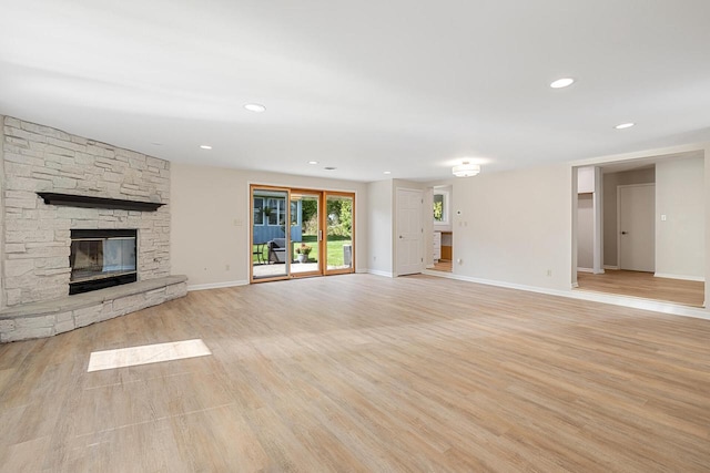 unfurnished living room with a stone fireplace and light hardwood / wood-style flooring