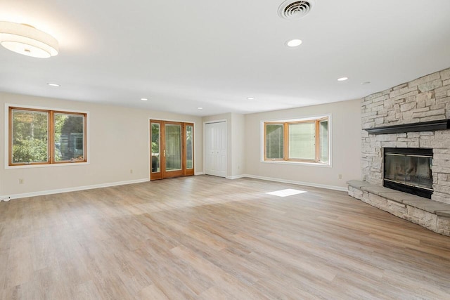 unfurnished living room featuring light hardwood / wood-style floors and a stone fireplace