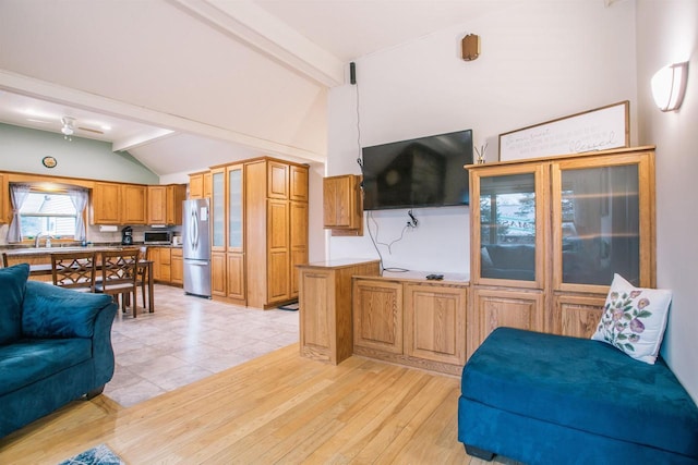 living room featuring vaulted ceiling with beams, light hardwood / wood-style flooring, and sink