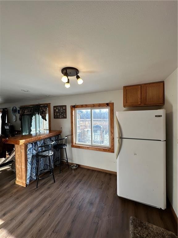 kitchen featuring dark hardwood / wood-style floors, white refrigerator, and a breakfast bar