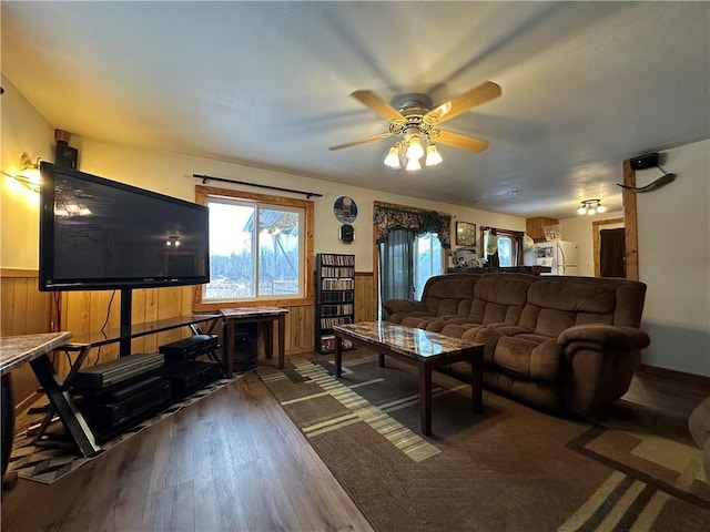 living room featuring dark hardwood / wood-style floors, wood walls, and ceiling fan