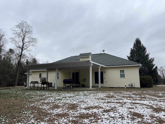 snow covered rear of property featuring a patio area