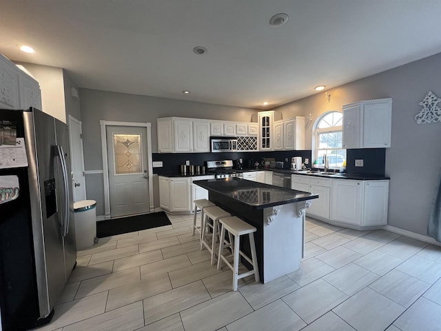 kitchen featuring a center island, white cabinets, sink, a kitchen bar, and stainless steel appliances