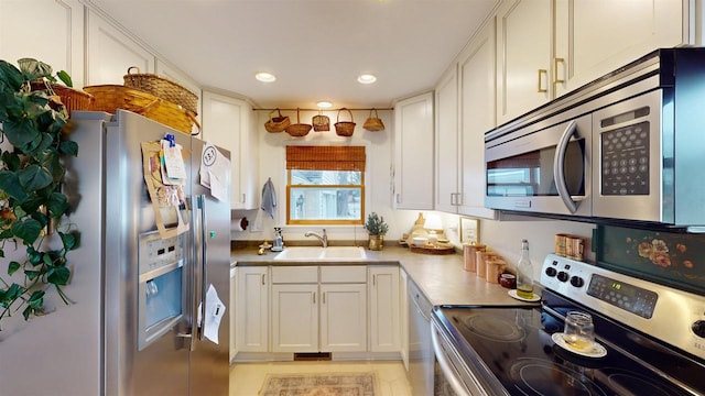 kitchen featuring sink, white cabinets, stainless steel appliances, and light tile patterned floors